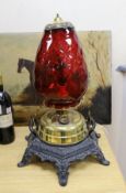 A floor-standing cranberry glass and brass, iron-mounted lamp, converted to a table lamp, 63cms