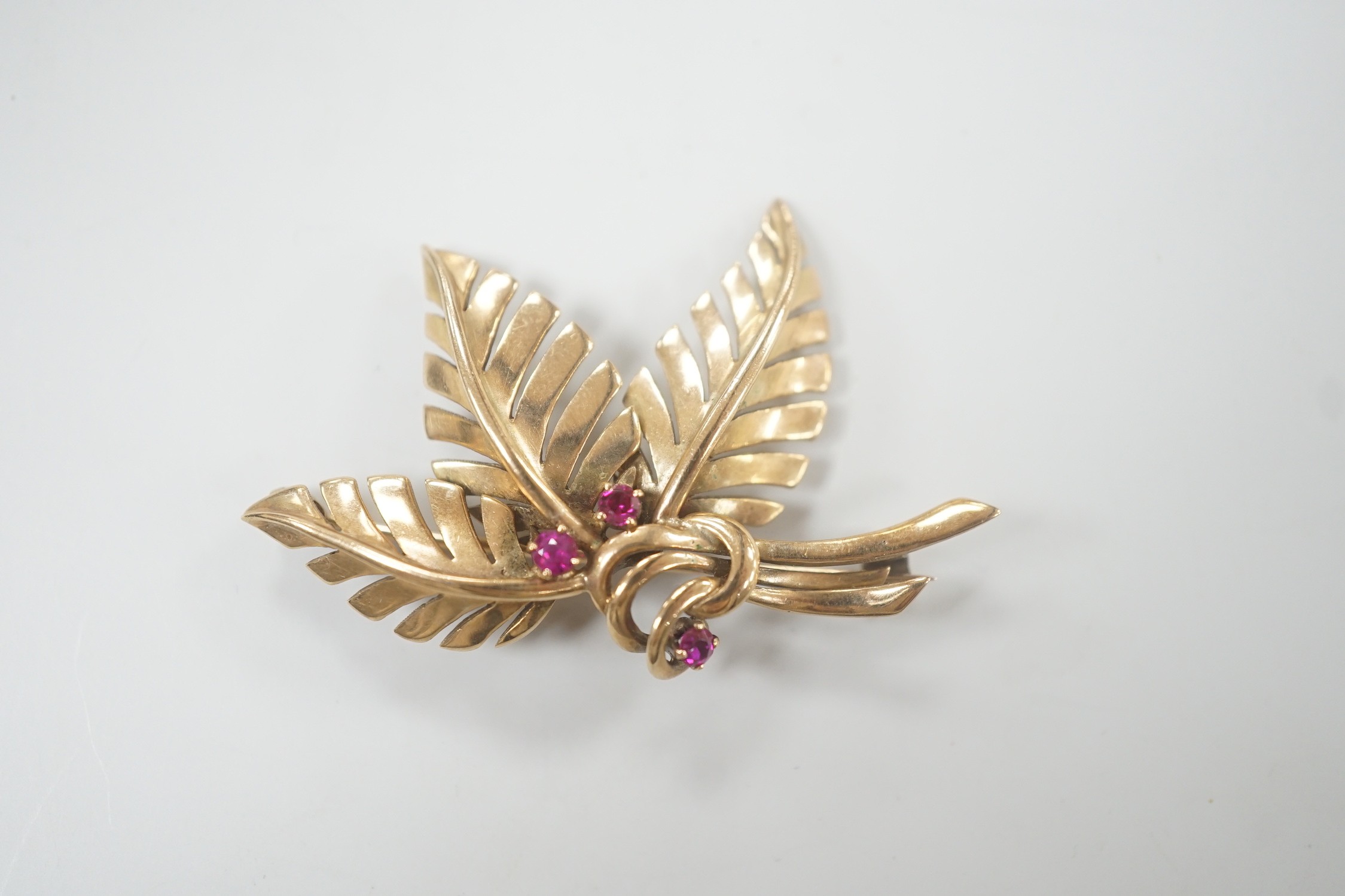 A yellow metal and three stone ruby set foliate brooch, 45mm, gross weight 6.8 grams. - Image 2 of 4