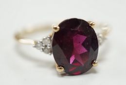 A modern 9ct gold, single stone oval cut garnet and six stone diamond chip set dress ring, size R/S,