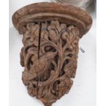 A Victorian/Edwardian carved pine wall bracket, carved with a bird within scrolling oak leaves,