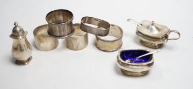 Five assorted silver napkin rings and a George V silver three piece condiment set.