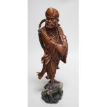 An early 20th century Chinese hardwood carving of a luohan, on soapstone base, 36cm tall