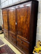 A late 18th century mahogany compactum wardrobe, fitted with three flame mahogany doors, length