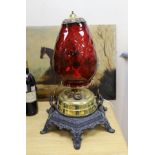A floor-standing cranberry glass, brass and iron-mounted lamp, converted to a table lamp, 63cms