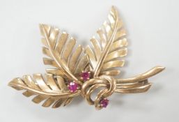 A yellow metal and three stone ruby set foliate brooch, 45mm, gross weight 6.8 grams.