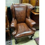 A George II style studded brown leather wing armchair, width 84cm, depth 86cm, height 108cm