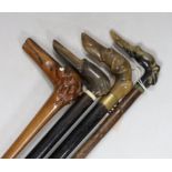 Four dog’s head walking sticks: three carved horn, one wood carved with bone eyes, longest 92cms