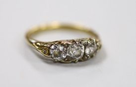 An antique yellow metal and graduated three stone diamond set ring, with diamond chip set spacers,