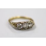 An antique yellow metal and graduated three stone diamond set ring, with diamond chip set spacers,