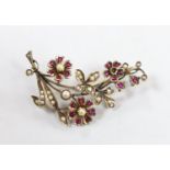 An early to mid 20th century, yellow metal, ruby and seed pearl cluster set floral spray brooch,