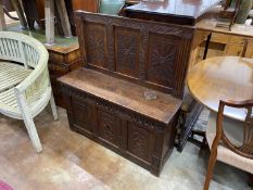 A carved and panelled oak settle incorporating old timber, width 106cm, depth 34cm, height 114cm
