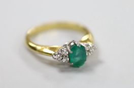 A modern 18ct gold and single stone oval cut emerald set ring, with six stone diamond chip set