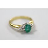 A modern 18ct gold and single stone oval cut emerald set ring, with six stone diamond chip set