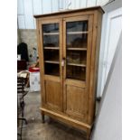 A Victorian glazed pine two door cabinet on stand, width 96cm, depth 27cm, height 182cm