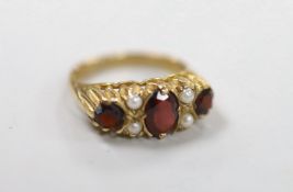 A 1970's 9ct gold, three stone garnet and four stone split pearl set half hoop ring, size K/L, gross