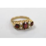 A 1970's 9ct gold, three stone garnet and four stone split pearl set half hoop ring, size K/L, gross
