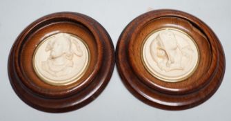 A pair of late 19th century carved and moulded composition portrait roundels, in oak frames