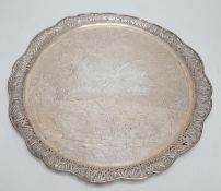 A Chinese Export white metal circular salver with pierced foliate wavy border and engraved with