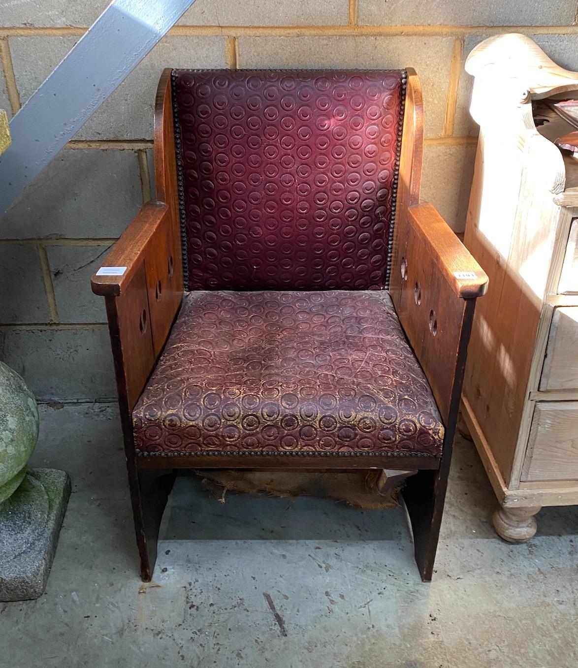 An early 20th century Arts & Crafts oak armchair, with pierced sides and embossed leather seat and