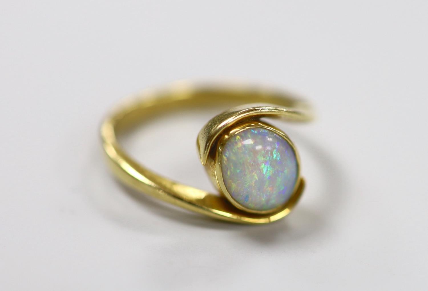 An 18ct and single stone oval white opal set ring, with crossover shoulders, size Q, gross weight
