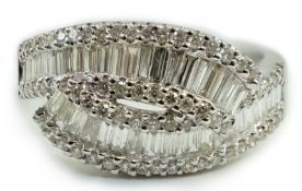 A modern 18ct white gold, baguette cut and diamond chip cluster set crossover ring, size O, gross