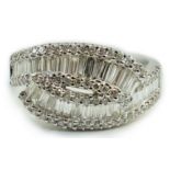 A modern 18ct white gold, baguette cut and diamond chip cluster set crossover ring, size O, gross