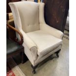 An early 20th century upholstered wing armchair, width 76cm, depth 78cm, height 102cm