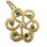 A modern yellow metal, emerald and diamond set stylised flower head pendant, 25mm, on a 375 chain,