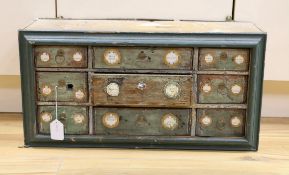 An early 20th century painted nine drawer spice hanging cupboard, 62cms wide, 31cms high