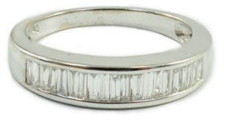 A modern white metal and graduated baguette cut channel set diamond half hoop ring, size M/N gross