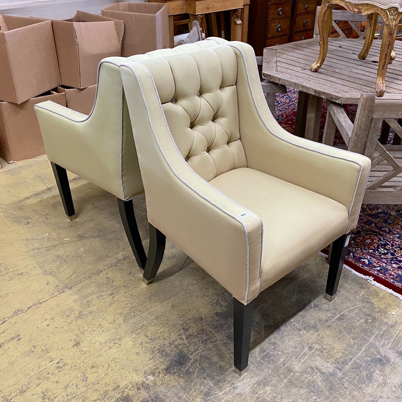 A pair of contemporary armchairs with deep buttoned backs on ebonised underframes, width 64cm, depth