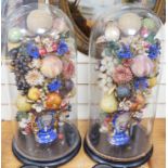 A pair of Victorian displays of painted papier mache fruit in vases, under glass domes, 58cms high