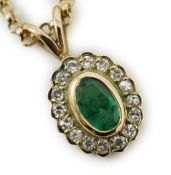 A modern 9ct gold, emerald and diamond set oval cluster pendant, 16mm, on a 9ct gold chain, 44cm,