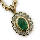 A modern 9ct gold, emerald and diamond set oval cluster pendant, 16mm, on a 9ct gold chain, 44cm,