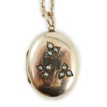 An Edwardian yellow metal and seed pearl set oval locket pendant, 25mm, on a 9ct chain, 47cm,