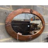 An Arts & Crafts embossed copper oval wall mirror, width 92cm, height 60cm