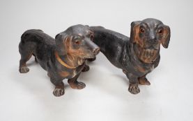 A pair of Austrian cold painted terracotta models of Dachshunds, one paw damaged, inset glass eyes