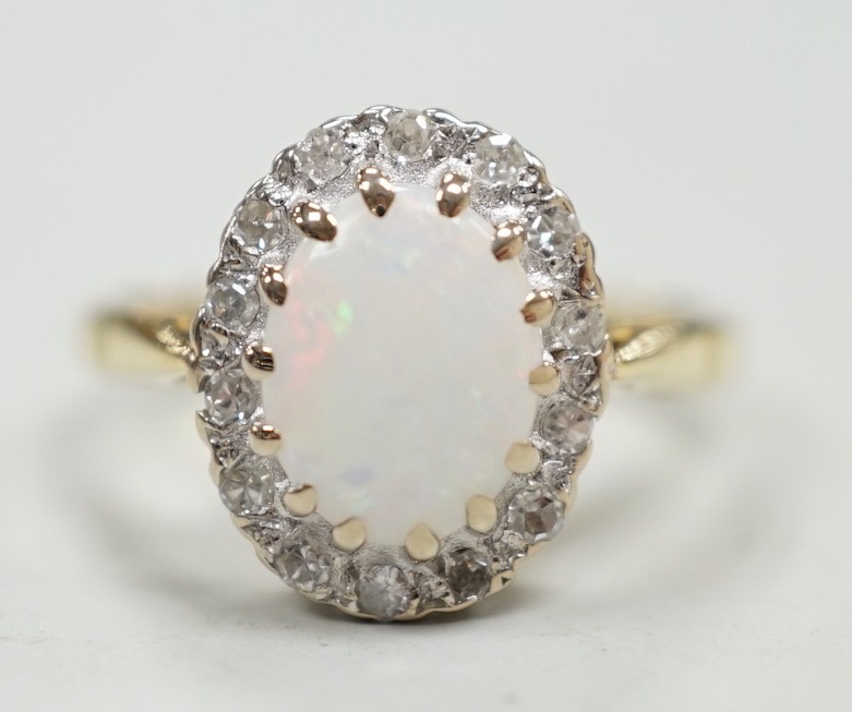 A modern 18ct white gold white opal and diamond set oval cluster ring, size M, gross weight 4.3