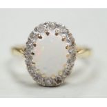 A modern 18ct white gold white opal and diamond set oval cluster ring, size M, gross weight 4.3