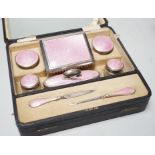 A cased George V nine piece silver and pink enamel mounted manicure set.