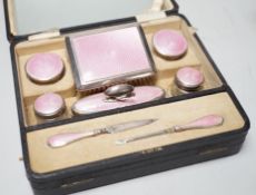 A cased George V nine piece silver and pink enamel mounted manicure set.