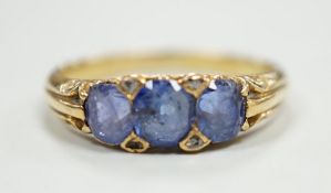 An early 20th century 18ct and three stone sapphire set half hoop ring, with diamond chip spacers,