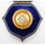 A cased Victorian yellow metal, enamel and split pearl set circular mourning pendant brooch, the