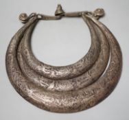 A Chinese Miao white metal triple necklace, repousse worked with dragons and twin fish, 25cm wide