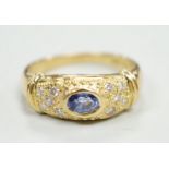 A modern 18ct gold, single stone oval cut sapphire and ten stone diamond chip set ring, size N/O,