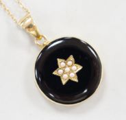 A late Victorian 15ct, black enamel and seed pearl set circular mourning locket, diameter 23mm, on a