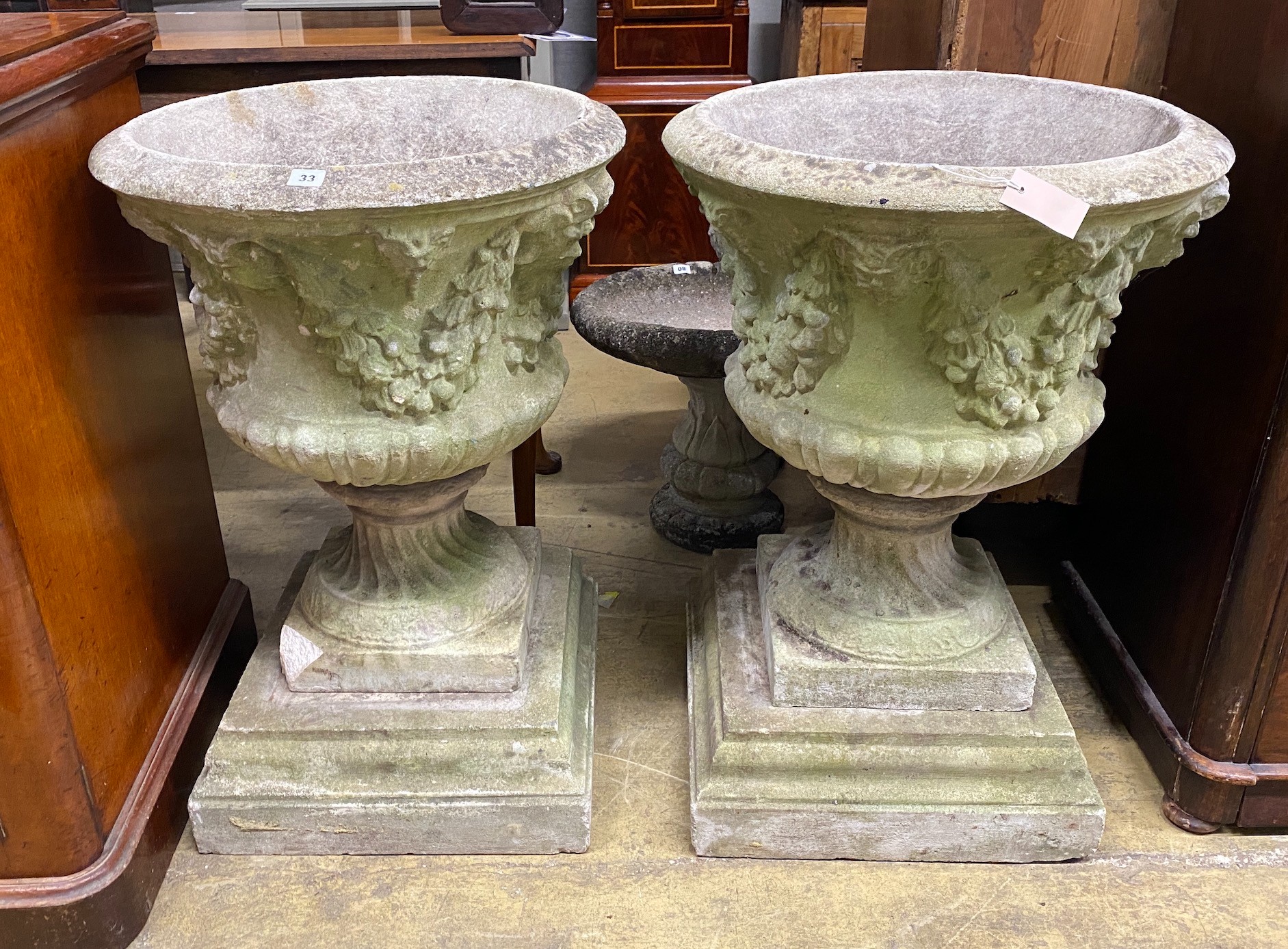 A pair of circular reconstituted campana garden urns with floral swagged bodies, diameter 59cm,