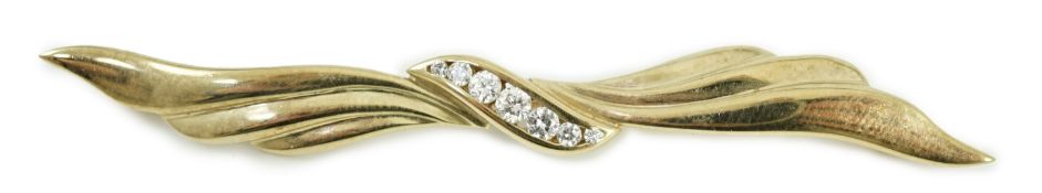 A modern 9ct gold and graduated seven stone diamond set wavy bar brooch, 68mm, gross weight 5.3