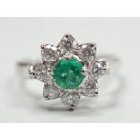 A modern 18k white metal, emerald and diamond set flower head cluster ring, size N, gross weight 4.5