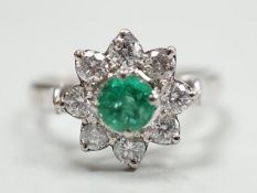 A modern 18k white metal, emerald and diamond set flower head cluster ring, size N, gross weight 4.5